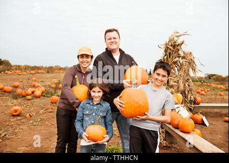 Portrait von lächelnden Familie holding Kürbisse und stehen auf gegen den klaren Himmel Stockfoto