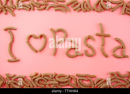 Ich liebe pasta Inschrift mit braunen Makkaroni auf rosa Hintergrund gemacht Stockfoto