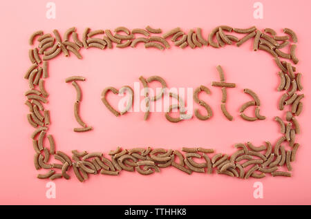 Ich liebe pasta Inschrift mit braunen Makkaroni auf rosa Hintergrund gemacht Stockfoto