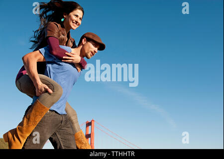 Low Angle Menschenbild huckepack Freundin gegen den blauen Himmel Stockfoto