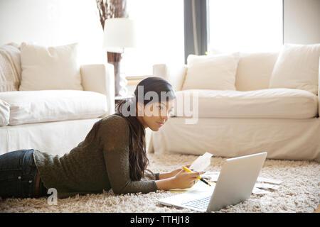 Ernsthafte Frau prüfen Rechnungen während der Verwendung von Laptop zu Hause Stockfoto