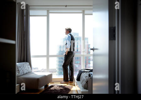 Nachdenklich Geschäftsmann, stehen, Fenster aus Glas, durch Eingang gesehen Stockfoto