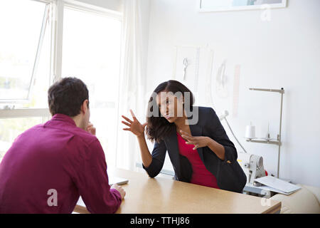 Geschäftskollegen, die sich am Schreibtisch im Büro unterhalten Stockfoto