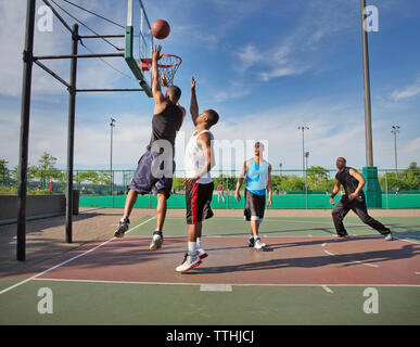 Männer Basketball spielen im Hof an einem sonnigen Tag Stockfoto