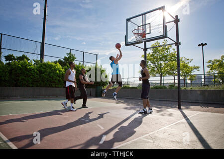 Freunde Basketball spielen im Hof an einem sonnigen Tag Stockfoto