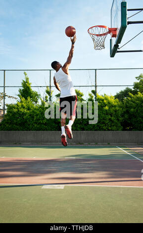 Ansicht der Rückseite des Sportlers dunking Ball in Hoop am Hof Stockfoto