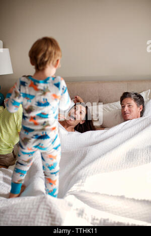 Glückliche Eltern betrachten Sohn am Bett Stockfoto