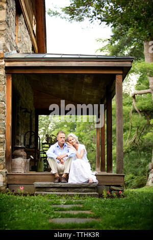Senior Paar sitzen auf der Veranda von Bäumen Stockfoto
