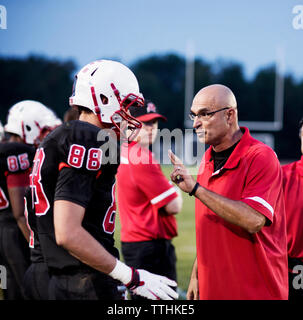 Trainer erklären, American Football Spieler auf dem Feld Stockfoto