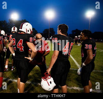 Ansicht der Rückseite des American Football Spieler hören auf Trainer auf Leuchtfeld Stockfoto