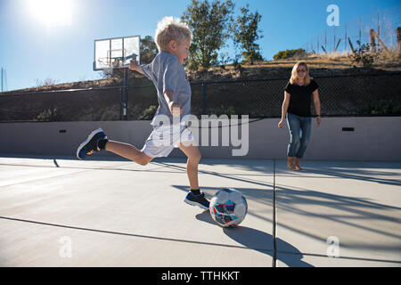 Junge kicking Ball beim Fußball spielen mit Mutter Stockfoto