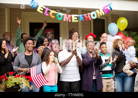 Glückliche Familie und Freunde willkommen beim Stehen vor dem Haus Stockfoto