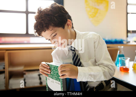 Schüler entfernen Buch aus der Tüte im Labor Stockfoto