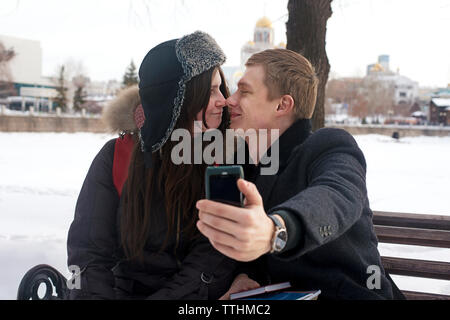 Romantischen Mann unter selfie mit Freundin sitzt auf der Bank im Park Stockfoto