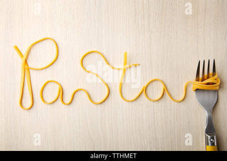 Wort PASTA aus gekochten Spaghetti mit Gabel auf Holz- Hintergrund Stockfoto