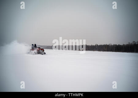 Freunde Reiten im Winter mit dem Schneemobil auf dem Feld Stockfoto