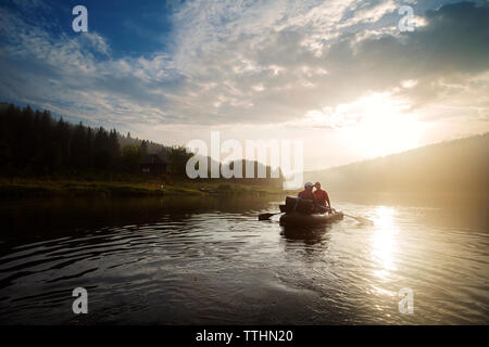 Mann und Frau River Rafting bei Sonnenuntergang Stockfoto