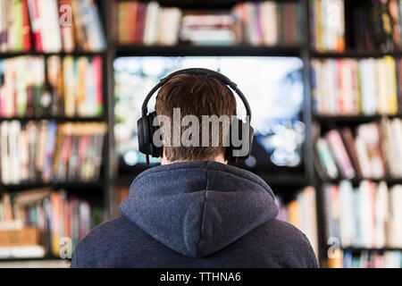 Junger Mann Videospiele auf Fernsehen von Büchern umgeben. Stockfoto