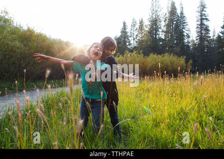 Mädchen umarmt Freund beim Stehen auf Gras gegen Sky Stockfoto