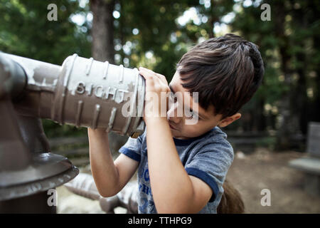 Junge Schauen durch Teleskop im Wald Stockfoto