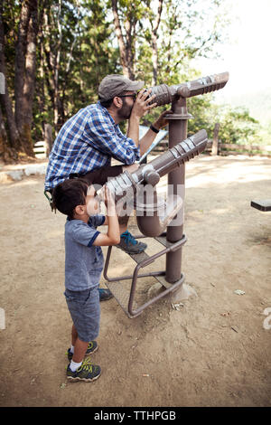 Vater und Sohn durch Teleskope im Wald suchen Stockfoto