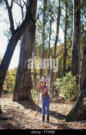 Girl holding Stick beim Stehen in Wald Stockfoto