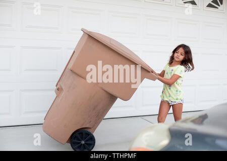 Mädchen ziehen Müll kann durch die Wand auf Bürgersteig Stockfoto