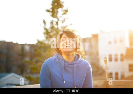 Fröhliche Frau stehend gegen Himmel bei Sonnenuntergang Stockfoto