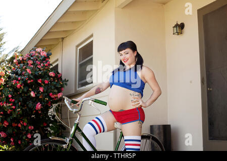 Porträt der Frau, die mit dem Fahrrad zu Hause Eingang Stockfoto