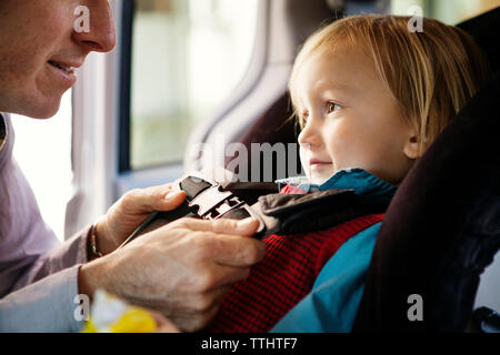 Zugeschnittenes Bild des Vaters Befestigung Sicherheitsgurt der Sohn im Auto. Stockfoto