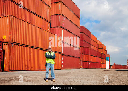 Portrait von zuversichtlich Mann mit verschränkten Armen stehend gegen Cargo Container Stockfoto