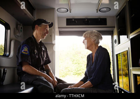 Sanitäter Lachen mit Patienten, während in Krankenwagen sitzen Stockfoto