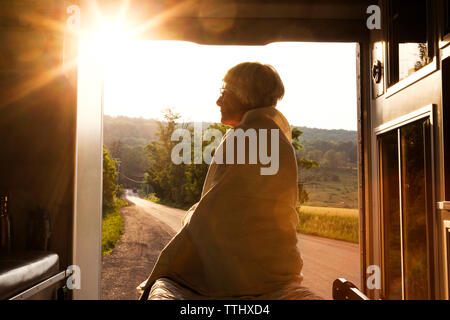 Frau aufgewickelt in der Decke sitzen in der Ambulanz bei Sonnenuntergang Stockfoto