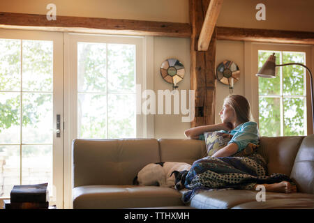 Nachdenkliche Frau sitzend auf Sofa zu Hause wegschauen Stockfoto