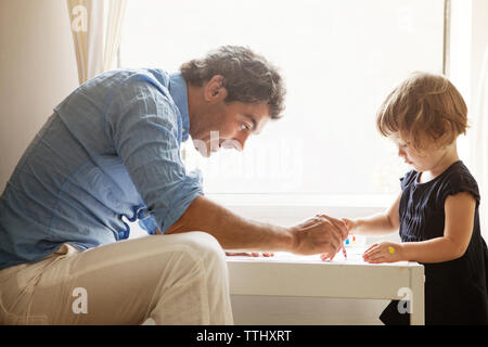 Vater lehre Tochter Färbung am Tisch in Home Stockfoto