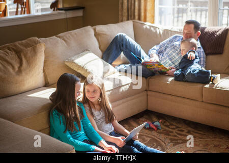 Vater lehre Sohn von Schwestern mit Tablette zu Hause Stockfoto