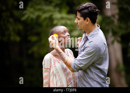 Seitenansicht des Menschen die Blume im Woman's Ohr Stockfoto