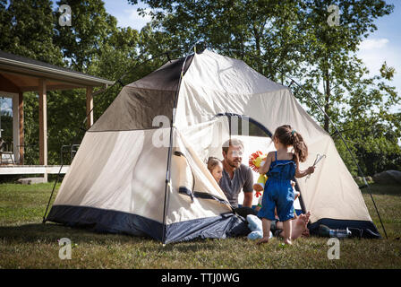 Vater mit Kindern auf der Suche nach Mädchen, während im Zelt sitzen Stockfoto