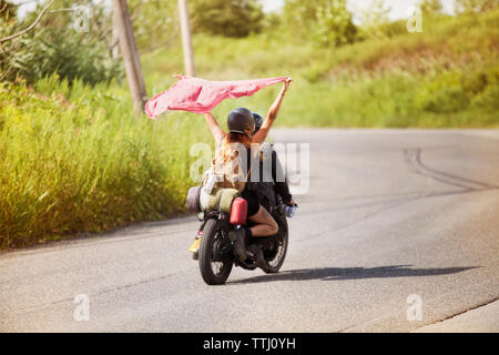 Frau mit aloft Schal beim Sitzen auf dem Motorrad mit Man Stockfoto