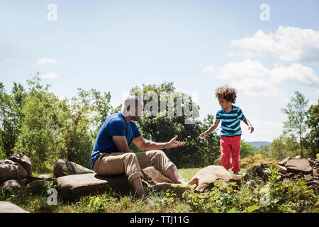 Vater und Sohn spielen mit Stein im Garten an einem sonnigen Tag Stockfoto