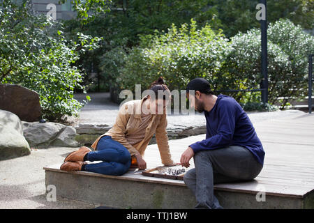 Paar Schach spielen beim Sitzen auf Diele in Rasen Stockfoto