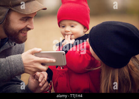 Vater, Smart Phone zu Baby im Park Stockfoto