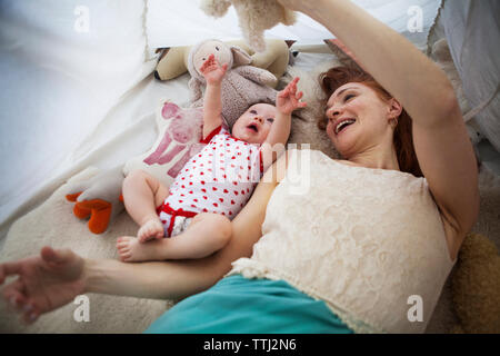 Mutter spielt mit Tochter, während im Zelt zu Hause liegen Stockfoto