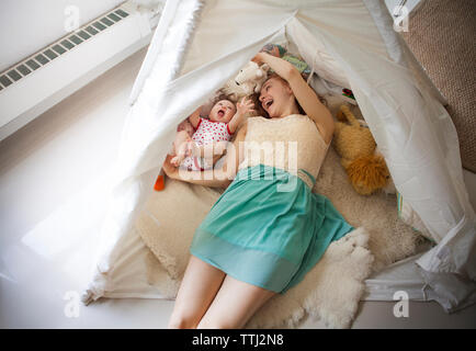 Hohe Betrachtungswinkel der Mutter spielt mit Tochter, während im Zelt zu Hause liegen Stockfoto