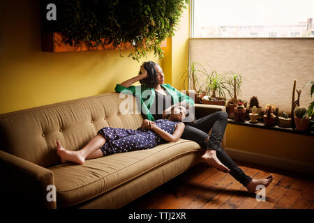 Mutter und Tochter weg schauen, und entspannen Sie auf dem Sofa zu Hause Stockfoto