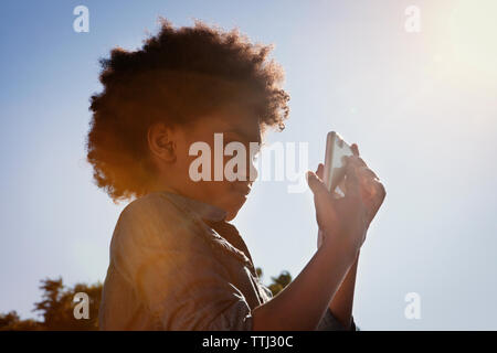 Low Angle View von Mädchen mit Handy vor klaren Himmel Stockfoto