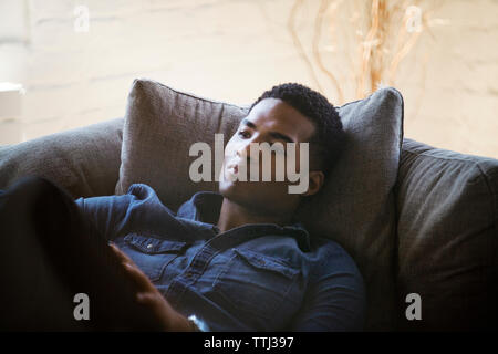 Nachdenklicher Mann auf dem Sofa zu Hause liegen Stockfoto