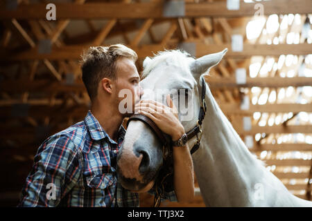 Low Angle View der Rancher küssen Pferd im Stall Stockfoto