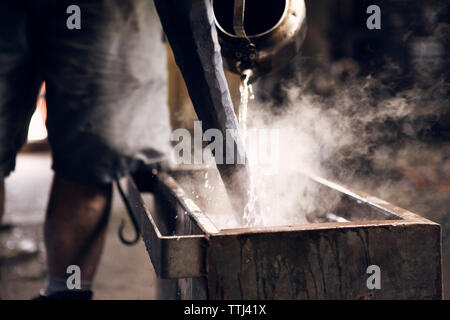 Mittelteil der Schmied gießt Wasser auf Hot Rod in der Werkstatt Stockfoto