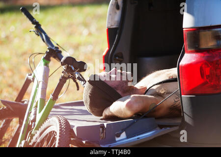 Mann schlafen im Kofferraum mit dem Mountainbike während der sonnigen Tag Stockfoto